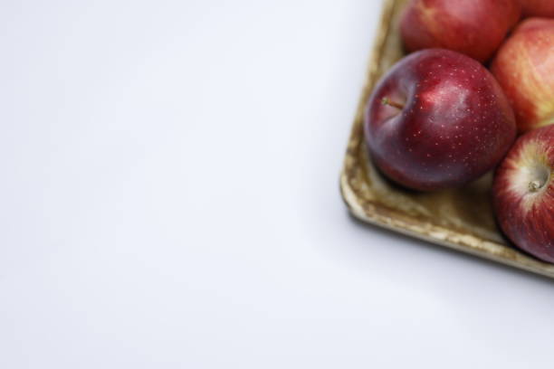 Istanbul, Turkey-March 21, 2021: Red apples on a wooden plate on a white background, Full Frame, Studio shot, Still life, Flat lay, Flash. Shot with Canon EOS R5.
