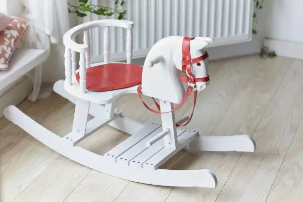 White wooden rocking horse chair in the home interior. Children toy