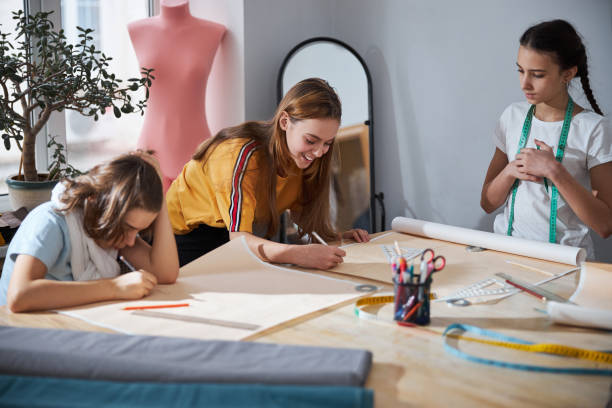 istock Cute girls drafting sewing patterns in dressmaking studio 1309464723