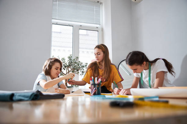 istock Adorable female children making sewing patterns in workshop 1309464727