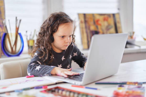istock Cute small preschool girl using a laptop for online education 1309466843