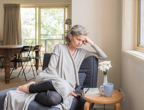 istock Middle aged woman using phone in living room 1309467191