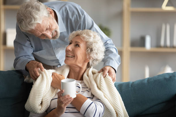 istock Affectionate elderly man covering shoulders of smiling wife with plaid. 1309468384