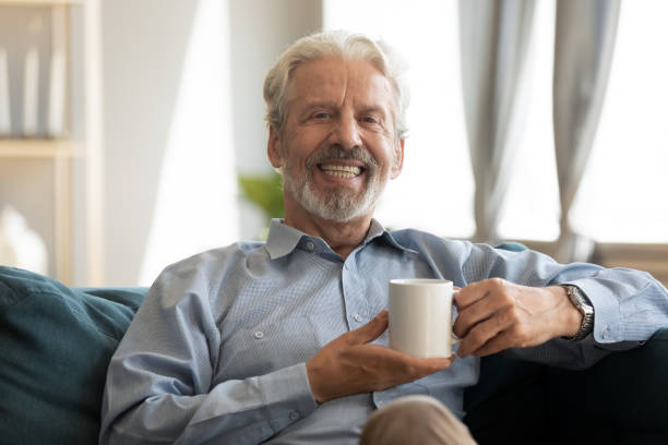 istock Happy mature man resting on sofa with coffee in hands. 1309468387