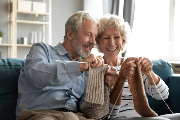 istock Happy mature woman teaching smiling older husband knitting. 1309468448