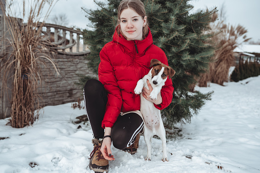 Teenage girl in winter outdoors in the snow with Jack Russell Terrier.