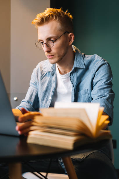 istock Caucasian man college student in glasses studying with laptop distantly preparing for test exam writing essay doing homework at home, distantly education concept.. 1309470265