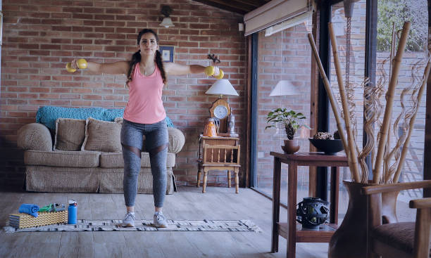 istock Hispanic young woman with dumbbells doing exercise at home. 1309479052