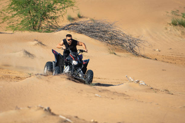 istock Muscular Man Riding Atv In the Desert 1309486710