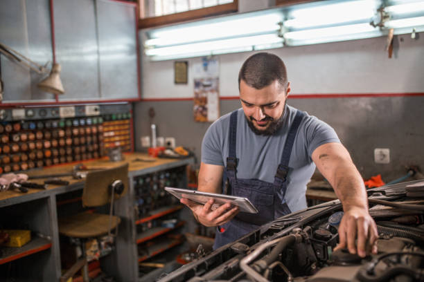 istock Car mechanic looking at tablet while analyzing engine in auto repair shop 1309487469