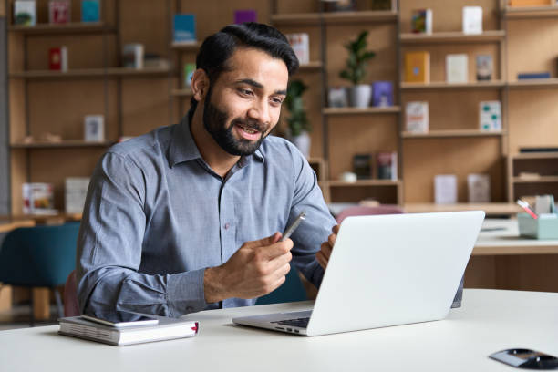 istock Young bearded indian business man teacher talking, teleworking, having virtual classroom meeting working on laptop computer giving online webinar training, remote class on video conference call. 1309489740