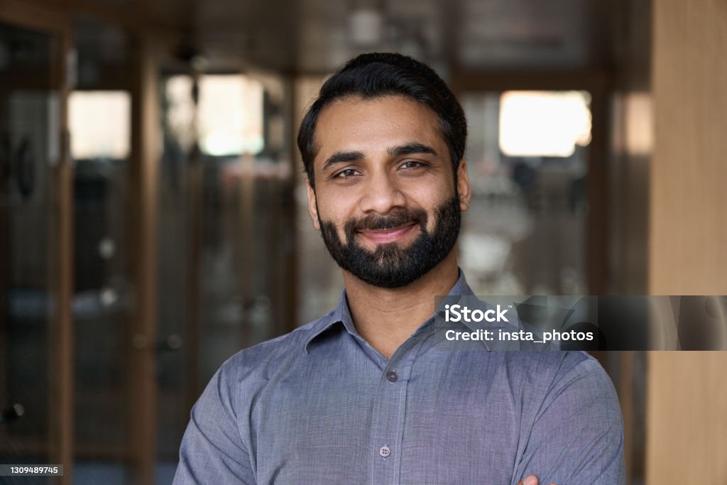 Portrait of young happy indian business man executive looking at camera. Eastern male professional teacher, smiling ethnic bearded entrepreneur or manager posing in office, close up face headshot. Men Stock Photo