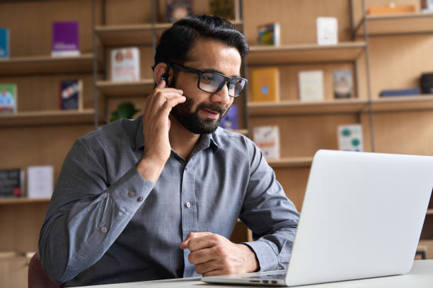 indian business man professional employee, remote consultant, customer service support manager wearing headset talking at virtual meeting consulting client on video call at home office call center. - 2603 imagens e fotografias de stock