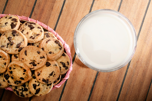Close up homemade chocolate chip cookies and glass of milk on wooden table