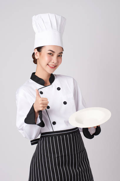 istock Beautiful young asian woman chef holding empty white plate on white background. 1309491791