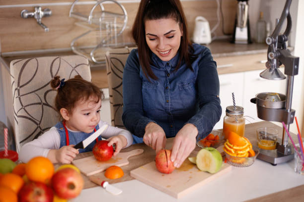 istock Mother and daughter squeezing oranges stock photo 1309494326