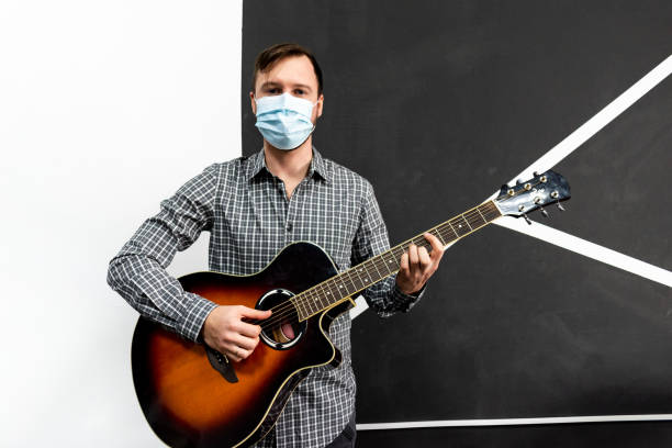 istock Young musician in protective mask practicing in playing guitar by focusing on hand and chords. 1309498146