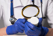 Doctor studying jar pf pills with magnifier