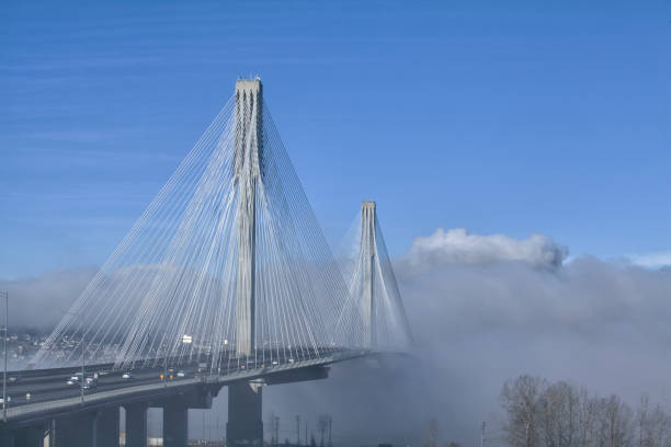 Port Mann Bridge in fog at Fraser river, BC, Canada Port Mann Bridge in fog seen from Surrey in winter. surrey british columbia stock pictures, royalty-free photos & images