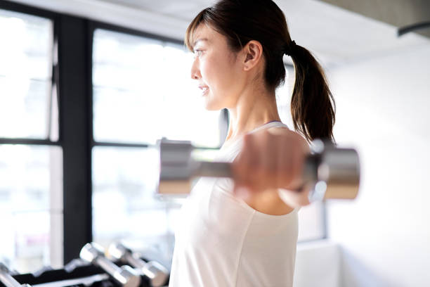 istock Asian woman doing dumbbell training indoors 1309511070