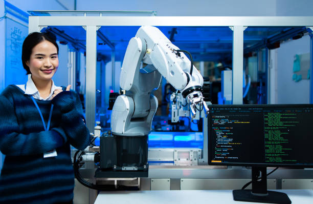istock Asian Engineers Maintenance Robot Arm at Lab. they are in a High Tech Research Laboratory with Modern Equipment. smiling multicultural businesspeople looking at camera while standing near robot. 1309514297