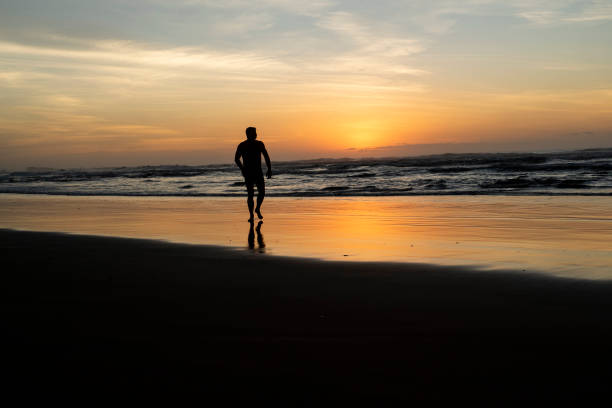 istock Man on beach at sunrise 1309514306