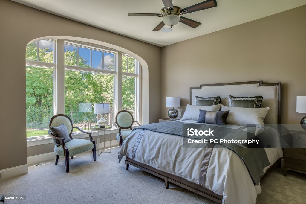 Huge windows for amazing view from bedroom Ceiling fan and sitting area for extra comfort while relaxing in master bedroom Owner's Bedroom Stock Photo