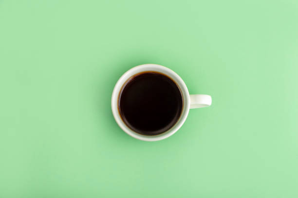 istock White cup with black coffee espresso on green background. Flat lay, minimalism, copy space for text. 1309519332