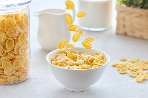 Traditional breakfast with cornflakes and milk. Cornflakes falling into a bowl.
