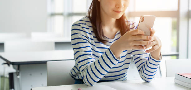 Young asian female student using a smart phone. Young asian female student using a smart phone. woman examining stock pictures, royalty-free photos & images