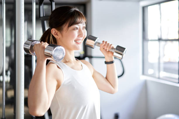 Asian woman doing shoulder press in training gym Asian woman doing shoulder press in training gym deltoid photos stock pictures, royalty-free photos & images