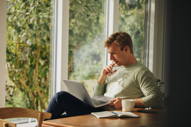 istock Man at home looking at laptop and thinking 1309529237
