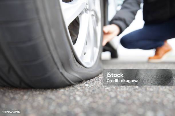 Man Touching A Flat Tire On The Roadside Stock Photo - Download Image Now - Flat Tire, Tire - Vehicle Part, Car