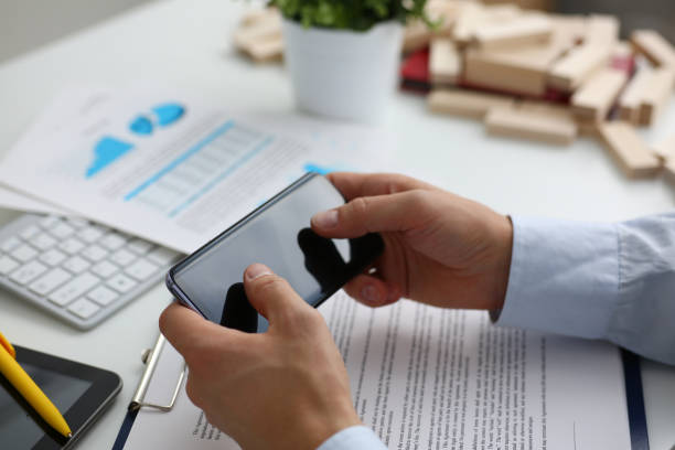 istock Businessman studying documents with help of smart phone 1309534603