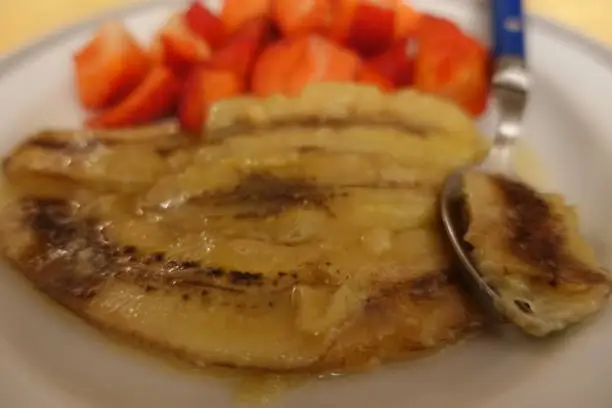 Flambéed bananas with rum served with portioned strawberries