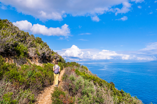 Tourist walking on the Sentiero dell'Amore, a footpath following the high, sheer cliffs connecting Ortano with Rio Marina on Elba