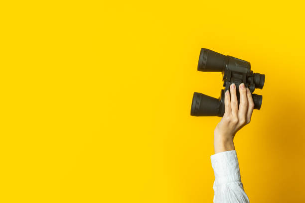 istock female hand holds black binoculars on a bright yellow background 1309537140