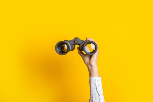 istock female hand holds black binoculars on a bright yellow background 1309537149