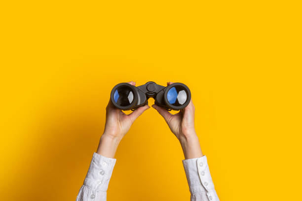 istock female hands hold black binoculars on a bright yellow background 1309537157