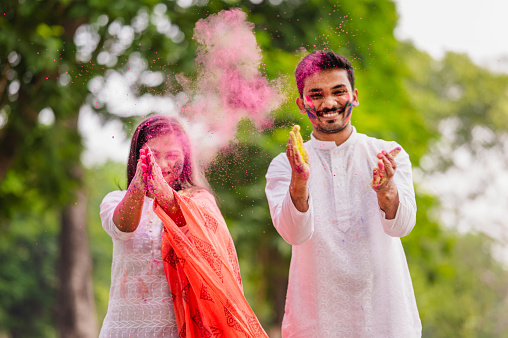Happy fun loving Asian / Indian couple painted in colors or gulal and celebrating holi festival outdoor. Concept of Indian festival Holi with Indian Couples.