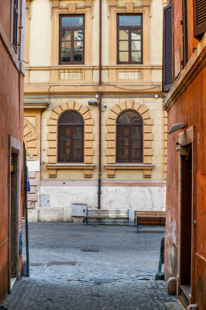 A glimpse of the ancient and narrow stone alleys of the Jewish Ghetto in the historic heart of Rome The Jewish elementary school along Via Portico d'Ottavia, in the heart of the Jewish ghetto of Rome. Located in the heart of the eternal city, the old Roman Jewish quarter is much loved for the facades of ancient and noble palaces with warm pastel tones, typical kosher restaurants, alleys and large pedestrian areas. Image in high definition format. ancient rome stock pictures, royalty-free photos & images