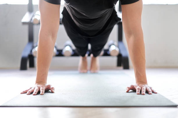 asiatische frau beim push-up in einem trainingsgymnasium - liegestütze stock-fotos und bilder