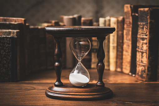 Antique hourglass and collection of old books: history and knowledge concept
