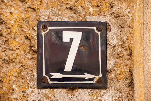 Weathered grunge square metal enamelled plate of number of street address with number 7