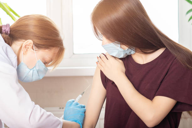 vaccination des adolescents dans les cliniques médicales, les écoles, un médecin donnant une injection à une fille dans un hôpital, une infirmière tenant une seringue avant d’administrer une dose de vaccin contre le coronavirus à partir de covid-1 - administering photos et images de collection