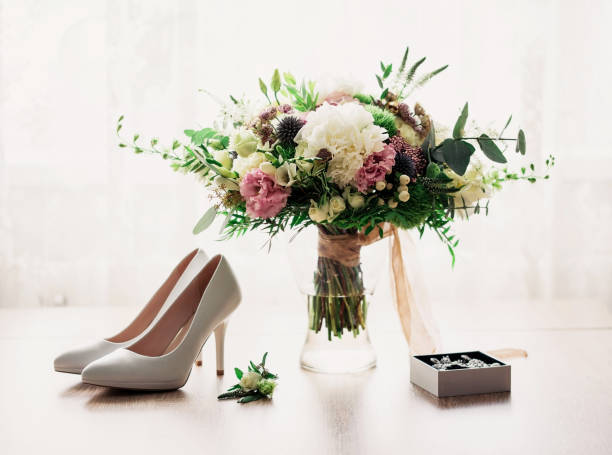 Bridal bouquet and white shoes on the table. Wedding accessories of the bride Bridal bouquet and white shoes on the table. Wedding accessories of the bride. Selective focus with blur wedding shoes stock pictures, royalty-free photos & images