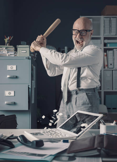 istock Crazy businessman destryoing his office with a baseball bat 1309547575