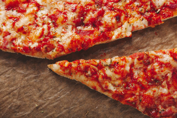 istock Homemade pizza with triangle slice laying on a brown baking paper 1309549436