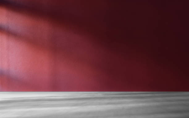 istock Red textured wall with grey concrete floor in empty room for displaying your product, light coming through window. 1309549944