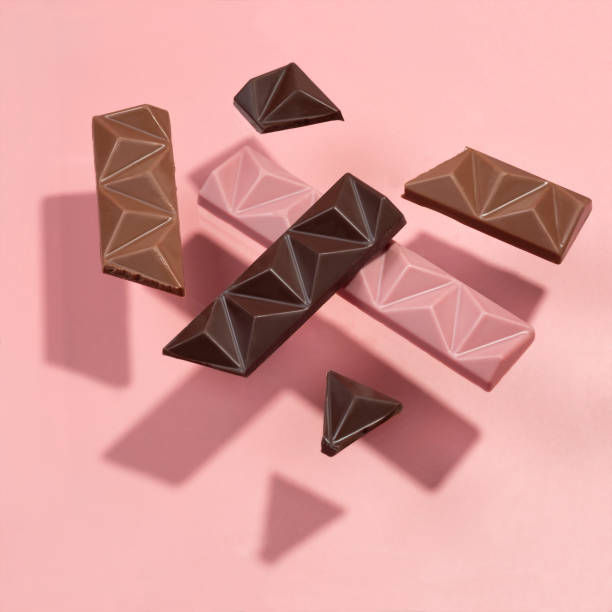 istock Abstract set of levitation colored chocolate on a pink background. Flying chocolate casts shadows 1309550797